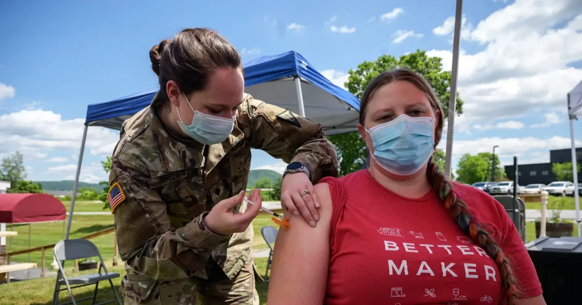 A photo of a person receiving a COVID-19 vaccine at an outdoor clinic.